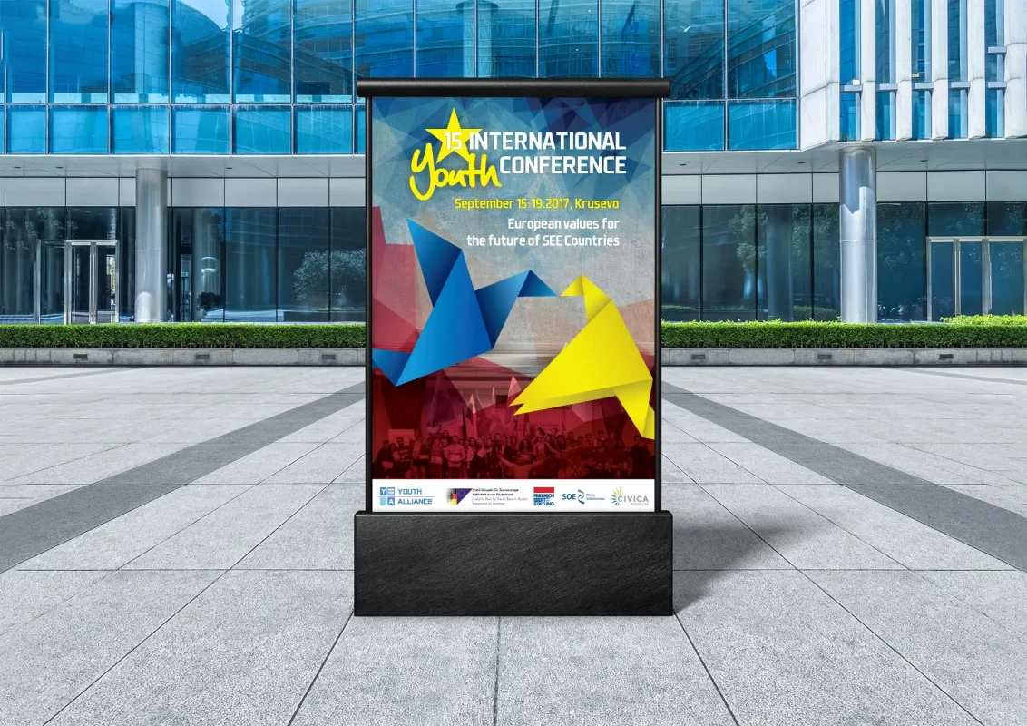 Billboard for the 15th International Youth Conference in front of a glass building.