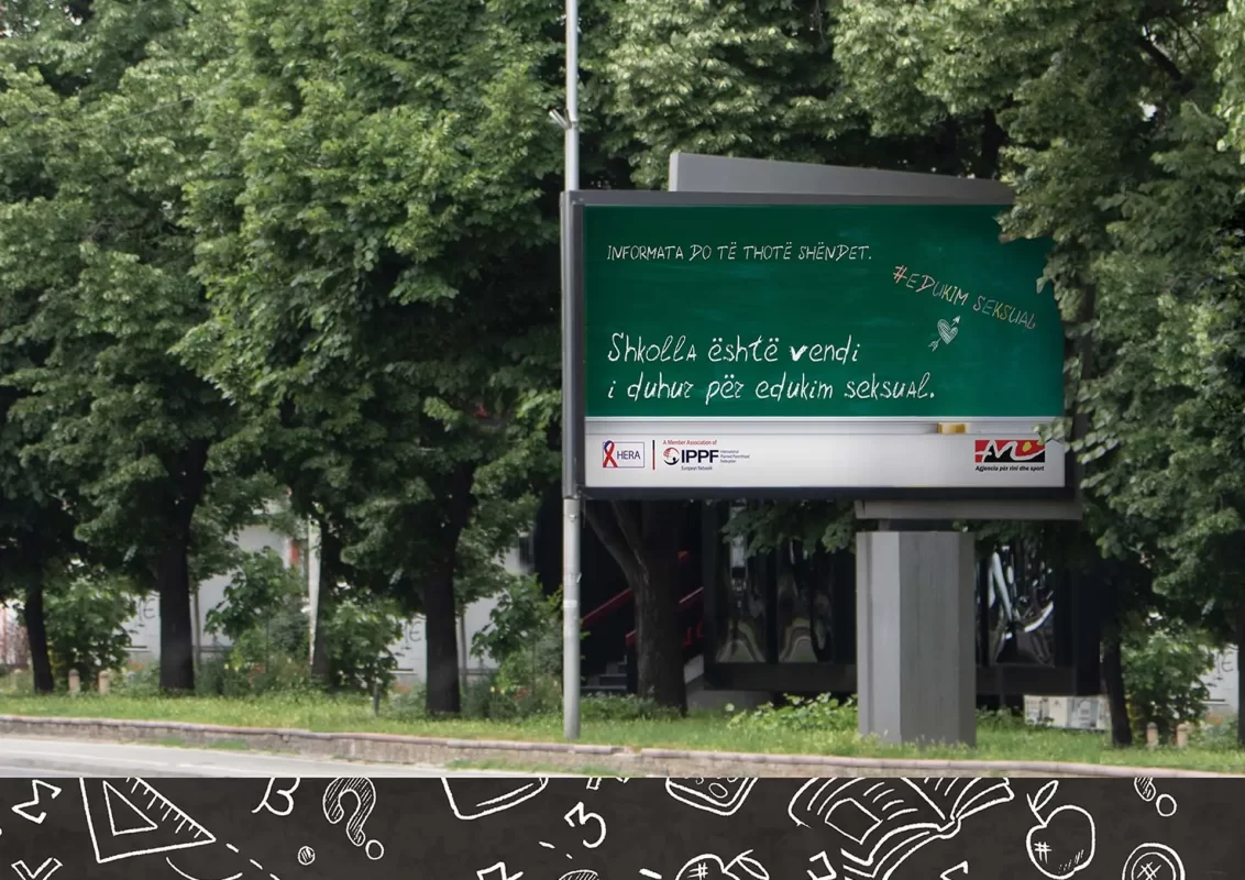 Billboard with text on chalkboard design advocating for sex education in schools, surrounded by trees.