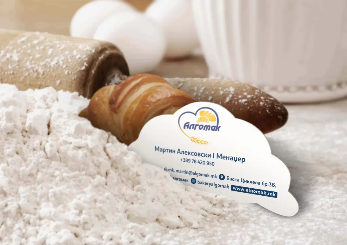 A rolling pin, croissant, and business card on a flour-dusted surface.