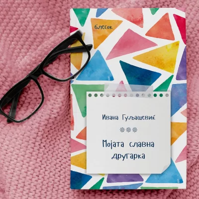 Colorful book cover with a pattern of geometric shapes and a pair of black glasses on a pink textured surface.