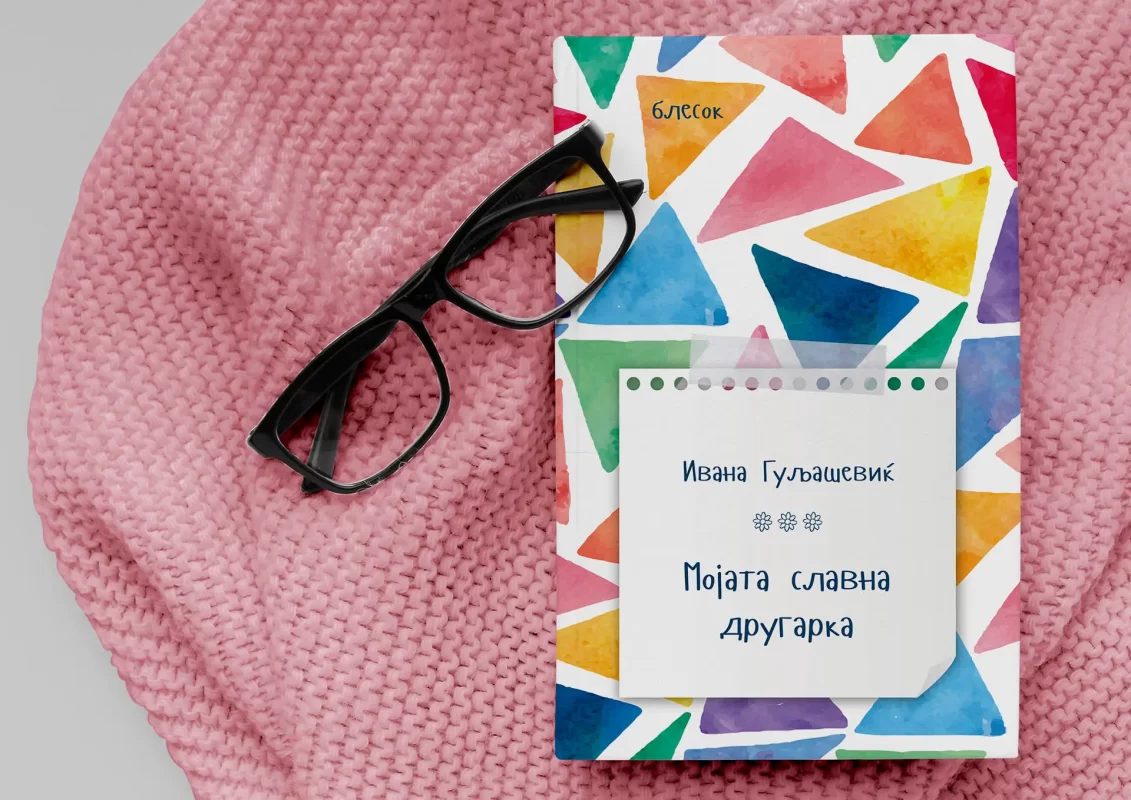 Book with colorful triangles, eyeglasses, on a pink knitted background.