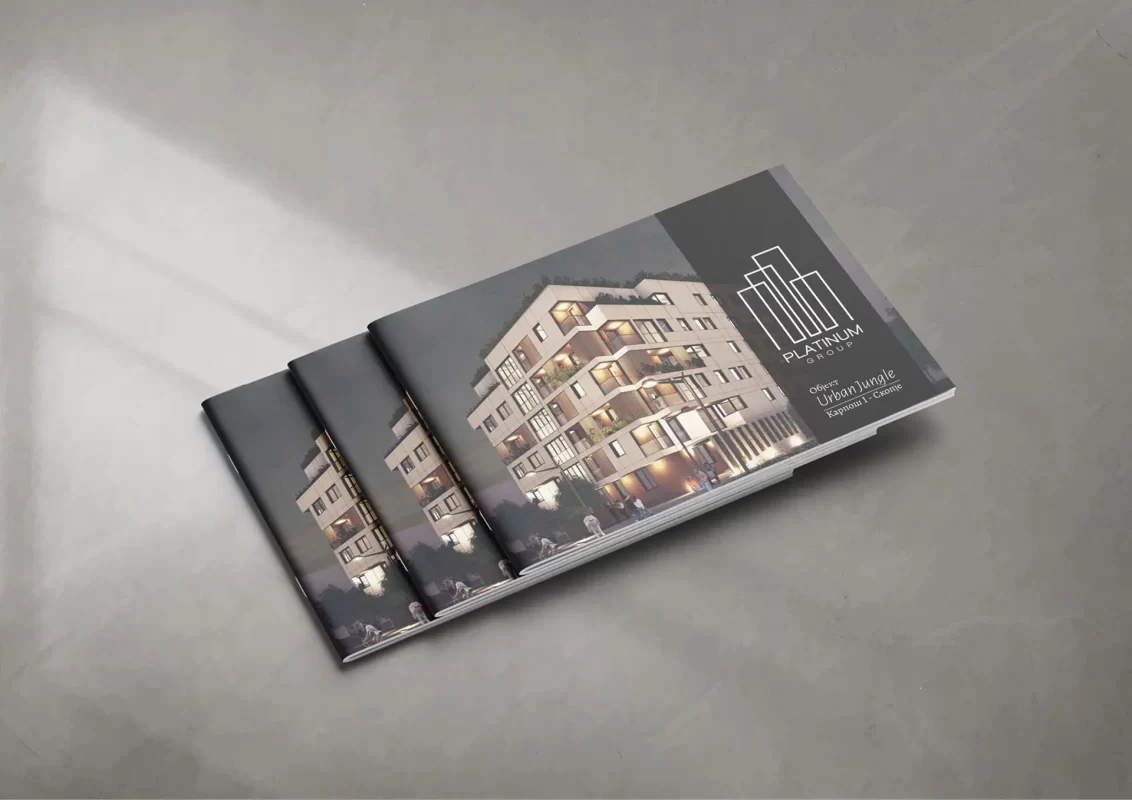 Three stacked real estate brochures on a grey surface featuring a lit building on the cover.