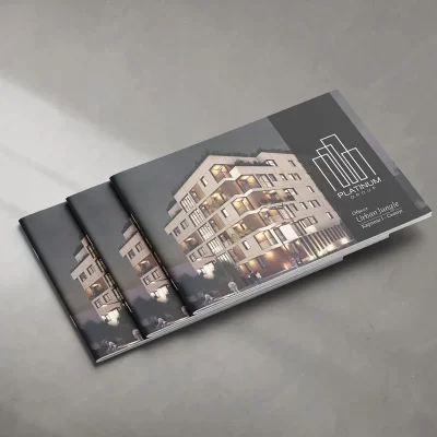 Three identical real estate brochures with a building's image on a gray surface.