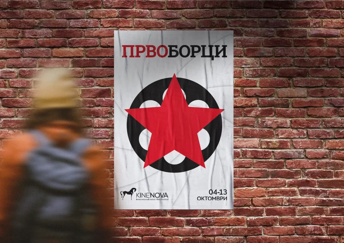 Blurred figure passing by a poster design with a logo on a brick wall.