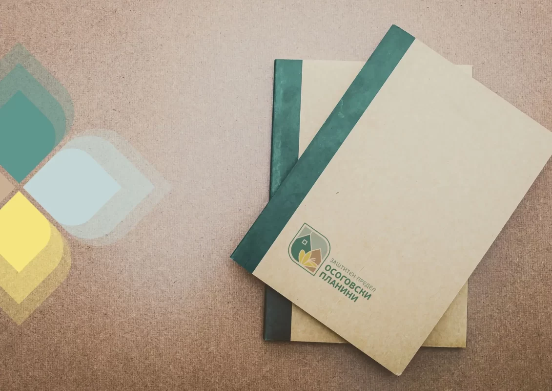 Two notebooks with a green logo on a textured surface, overlaid with semitransparent color shapes.