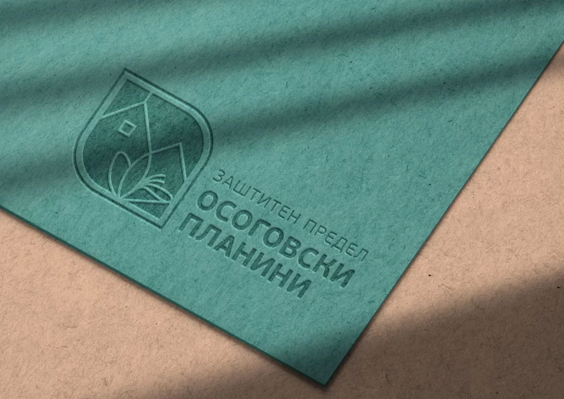 Embossed teal paper with Cyrillic text and geometric logo casting a shadow.