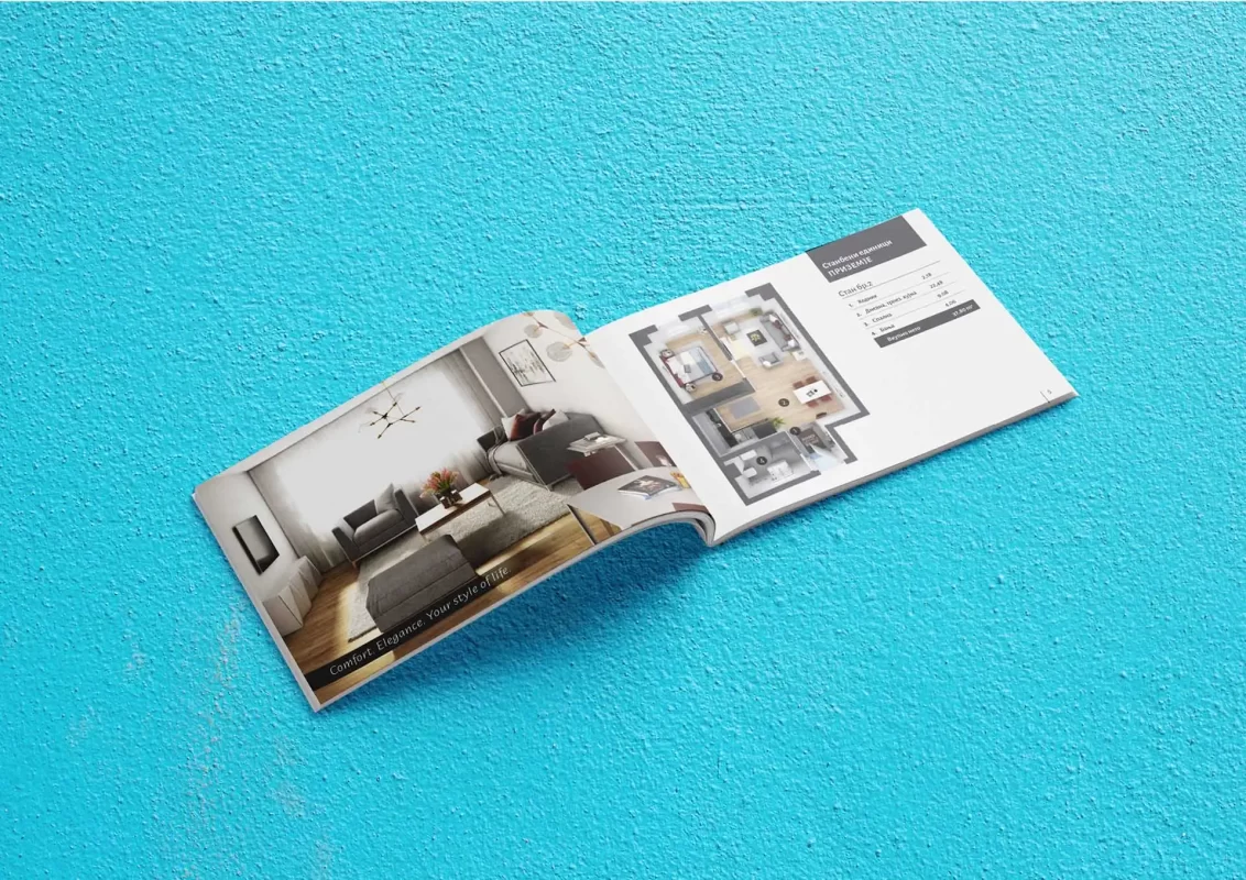 Open magazine with a living room design layout on a textured blue surface.