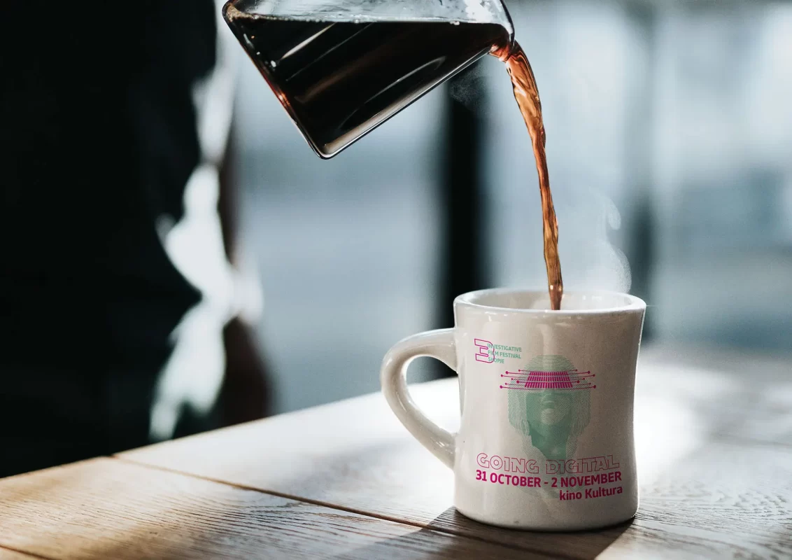 Coffee being poured into a mug on a wooden surface with a soft-focused background.