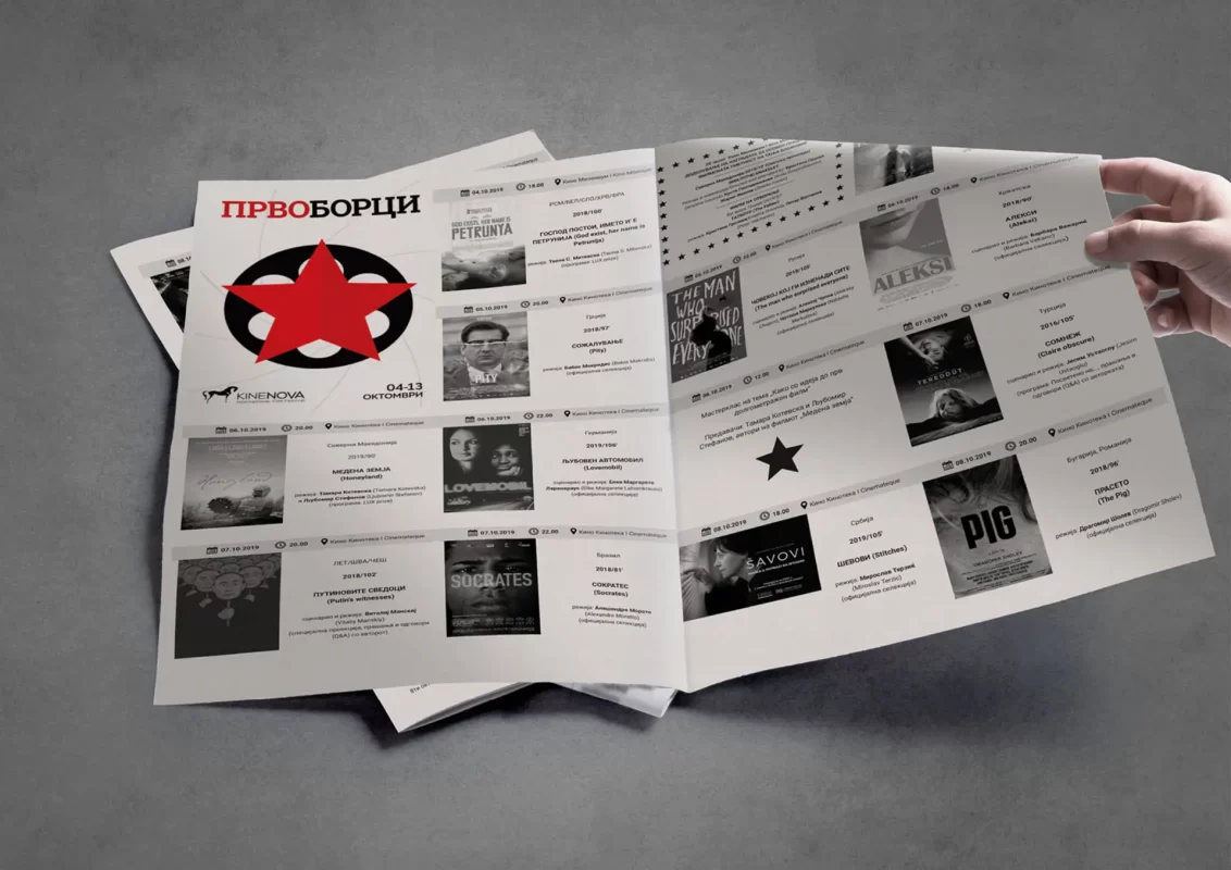 A hand holding an open film festival program with text and images.